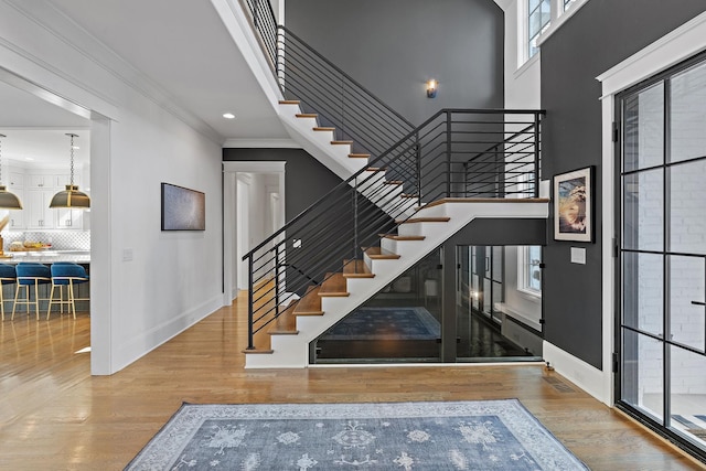 staircase with hardwood / wood-style flooring, ornamental molding, and a high ceiling