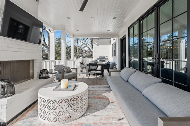 living room with an outdoor brick fireplace, wood ceiling, and a wall of windows