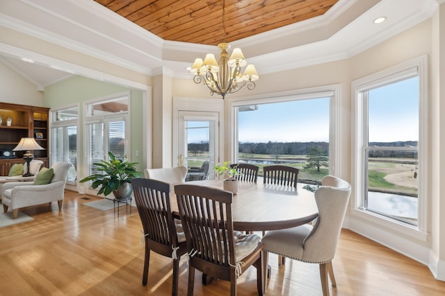 dining room with an inviting chandelier, a raised ceiling, and light hardwood / wood-style flooring