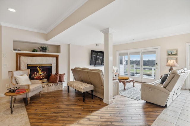 living room with ornate columns, a premium fireplace, ornamental molding, wood finished floors, and baseboards