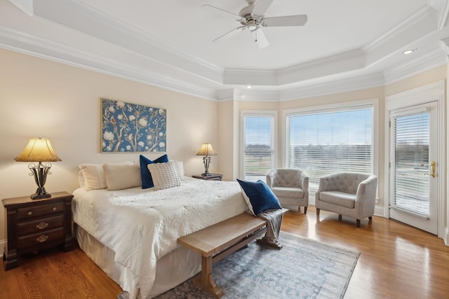 bedroom featuring crown molding, a tray ceiling, wood finished floors, and access to exterior