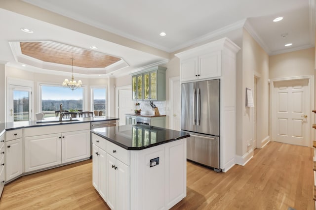 kitchen featuring dark countertops, appliances with stainless steel finishes, a center island, white cabinetry, and a sink