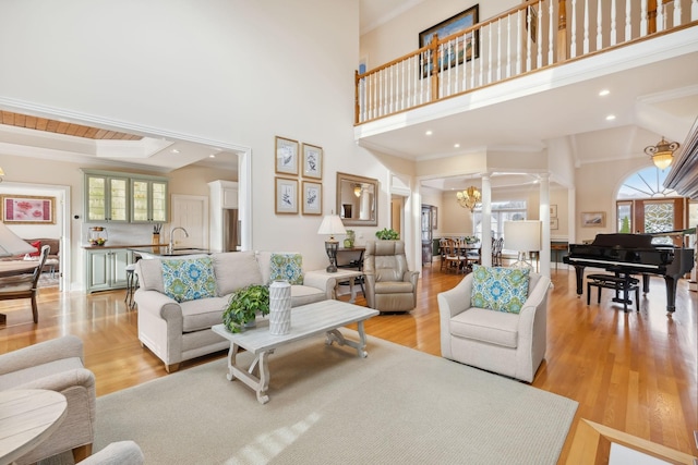 living area with light wood-type flooring, a wealth of natural light, decorative columns, and ornamental molding