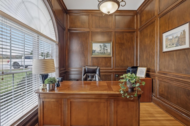 office area with wood walls, a decorative wall, and light wood finished floors