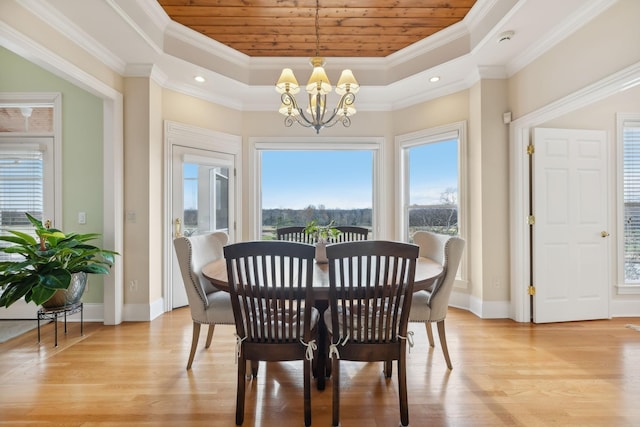 dining room featuring crown molding, a tray ceiling, a chandelier, and light wood-type flooring