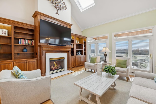 living area with high vaulted ceiling, a skylight, a glass covered fireplace, and crown molding