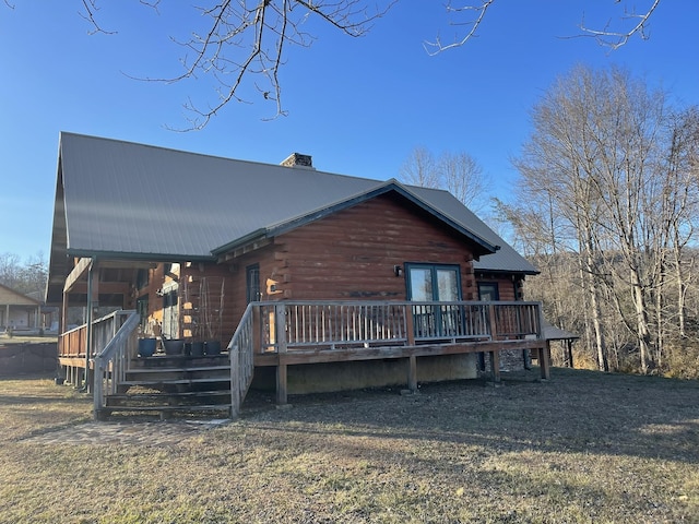 rear view of house with metal roof, a chimney, log siding, and a wooden deck