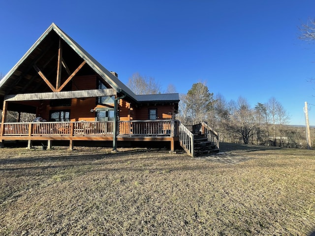 rear view of property featuring a deck and a lawn