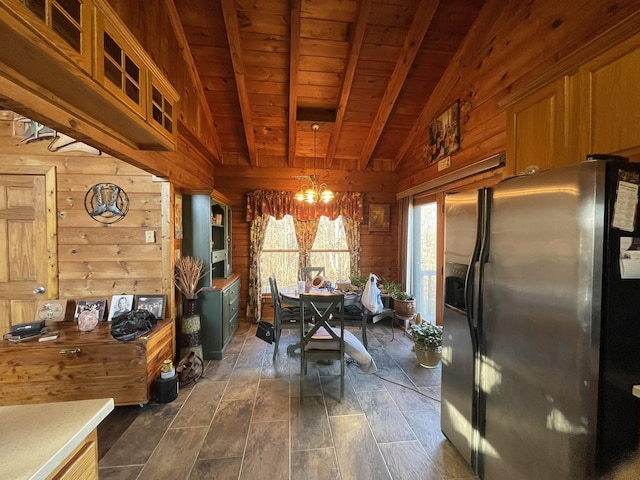 dining space with vaulted ceiling with beams, wood ceiling, an inviting chandelier, and wood walls