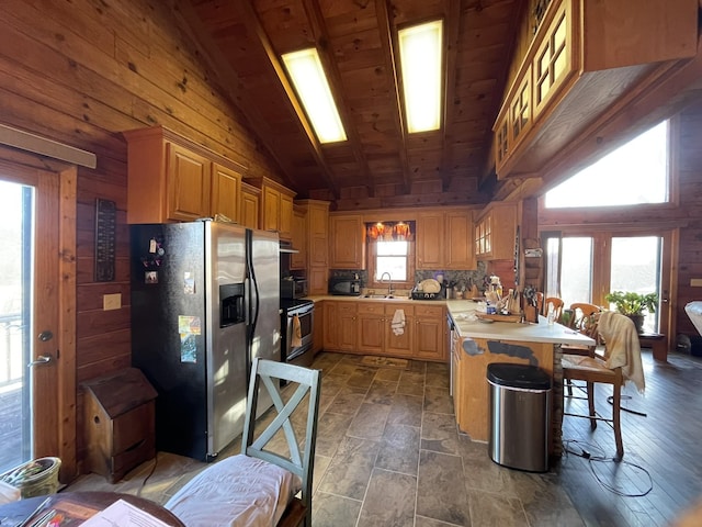 kitchen featuring stainless steel fridge with ice dispenser, a breakfast bar area, a peninsula, light countertops, and a sink