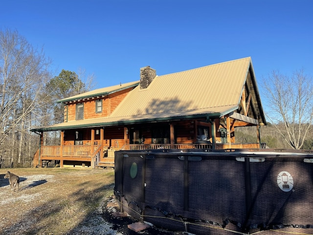 back of house featuring metal roof and a chimney