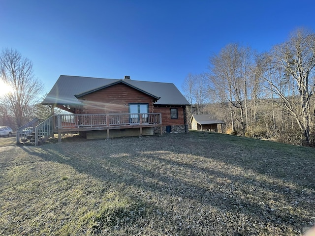 back of house with a chimney, log siding, and a wooden deck