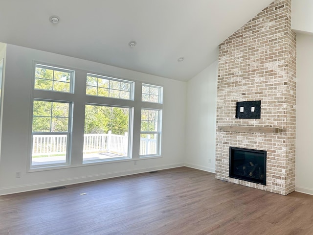 unfurnished living room with dark wood-type flooring, a fireplace, and high vaulted ceiling