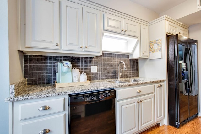 kitchen featuring tasteful backsplash, sink, light hardwood / wood-style flooring, and black appliances