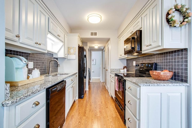 kitchen with white cabinetry, light stone countertops, sink, and black appliances