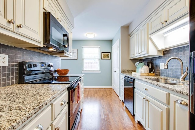 kitchen with sink, backsplash, black appliances, light stone countertops, and light wood-type flooring