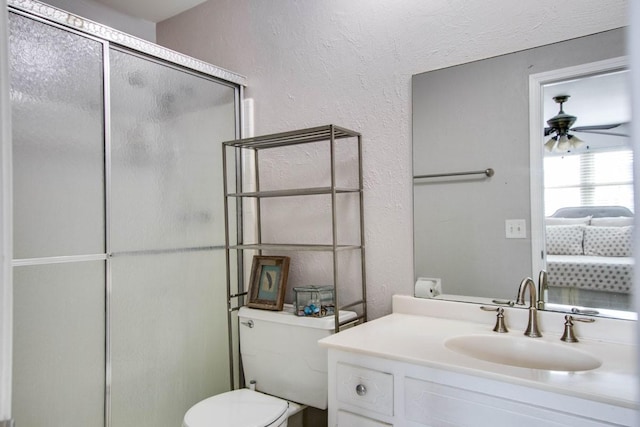 bathroom with vanity, a shower with door, toilet, and ceiling fan