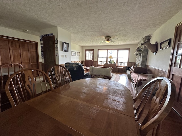 dining room with ceiling fan, a textured ceiling, and wood walls