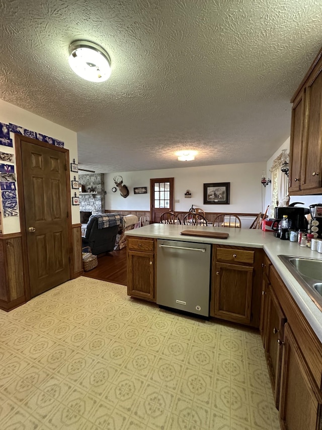 kitchen featuring sink, stainless steel dishwasher, kitchen peninsula, and a textured ceiling