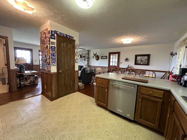 kitchen with wooden walls, dishwasher, and a textured ceiling