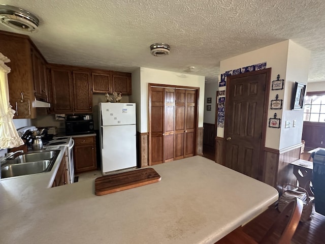 kitchen with sink, stove, white refrigerator, a textured ceiling, and kitchen peninsula