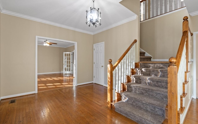 foyer entrance featuring ornamental molding, ceiling fan with notable chandelier, and hardwood / wood-style floors