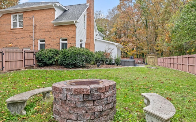 view of yard with an outdoor fire pit, a hot tub, and a shed