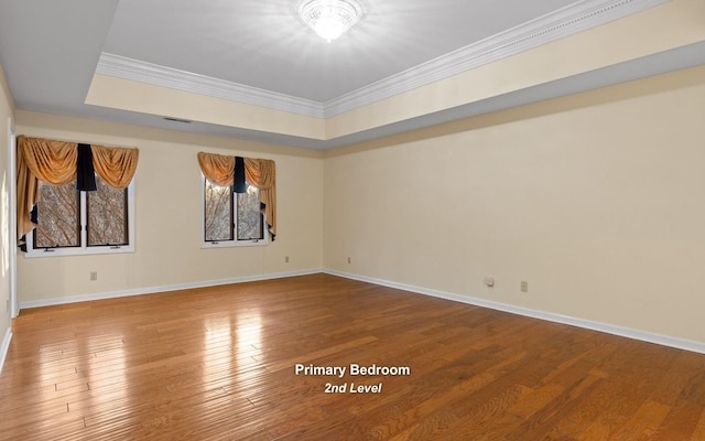 unfurnished room featuring ornamental molding, a raised ceiling, and hardwood / wood-style floors