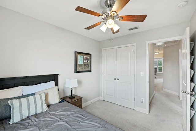 bedroom with ceiling fan, a closet, and light carpet