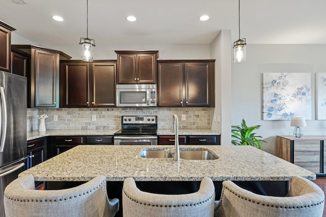 kitchen with pendant lighting, sink, a breakfast bar area, and appliances with stainless steel finishes