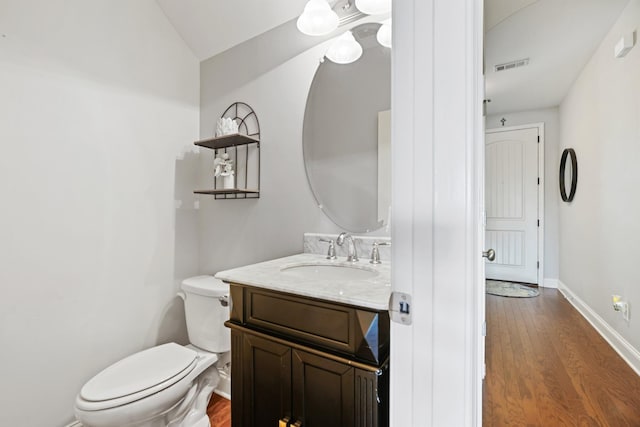 bathroom with vanity, hardwood / wood-style flooring, vaulted ceiling, and toilet