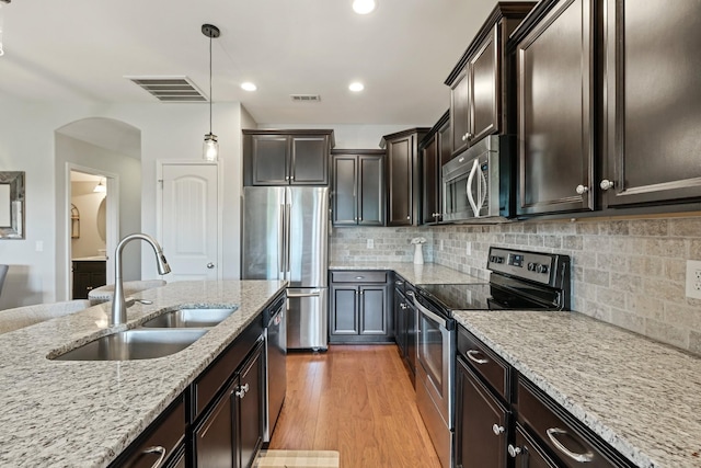 kitchen with pendant lighting, dark brown cabinetry, stainless steel appliances, and sink