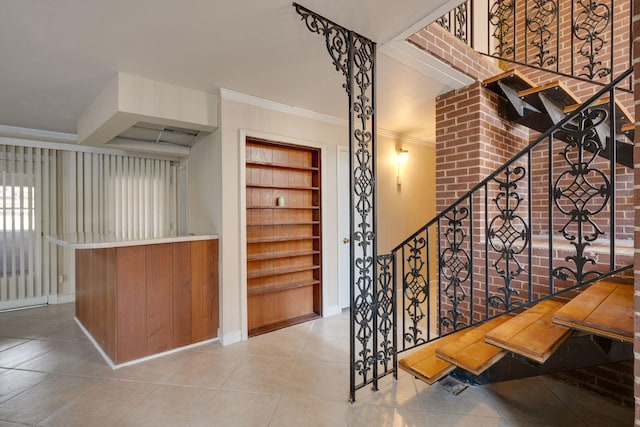 stairs featuring tile patterned flooring, crown molding, brick wall, and built in features