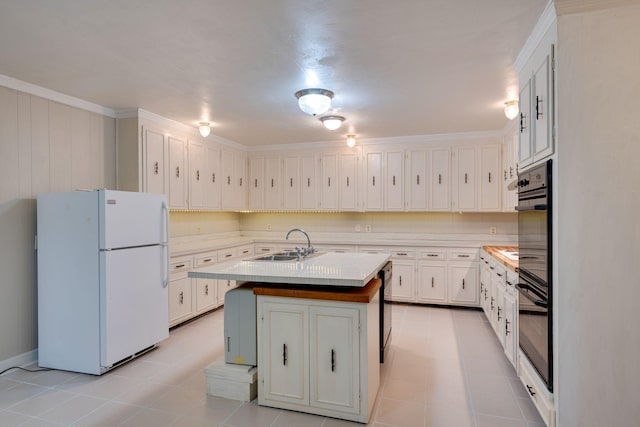 kitchen featuring white cabinetry, sink, a center island with sink, and white refrigerator