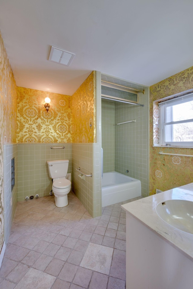 full bathroom with tiled shower / bath combo, vanity, tile walls, and toilet