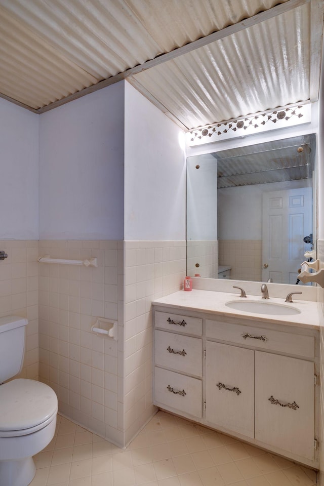 bathroom featuring vanity, tile walls, and toilet