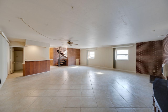 interior space with ceiling fan, brick wall, and light tile patterned floors