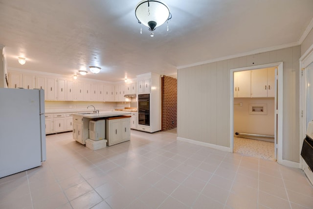 kitchen featuring ornamental molding, an island with sink, white fridge, and white cabinets