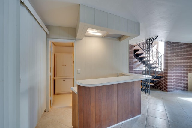 kitchen featuring light tile patterned flooring and brick wall