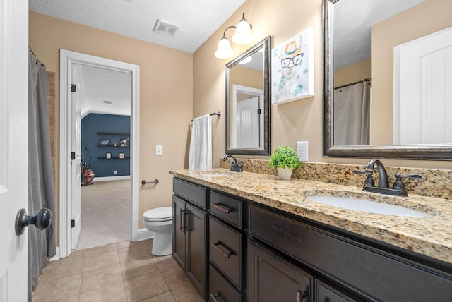 bathroom featuring tile patterned flooring, vanity, a textured ceiling, and toilet