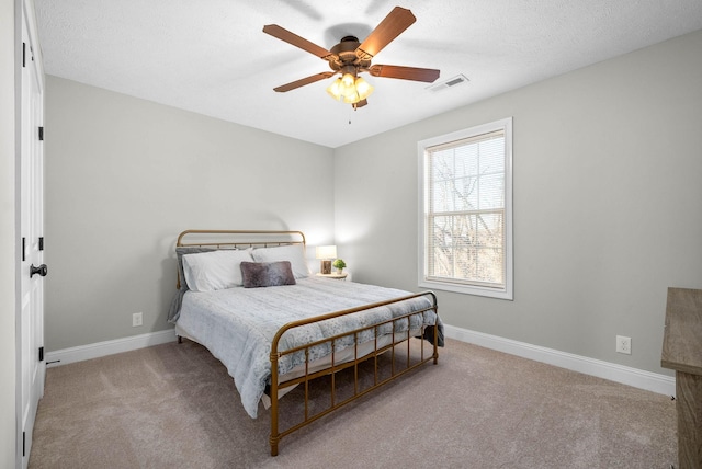 bedroom with ceiling fan, light carpet, and a textured ceiling