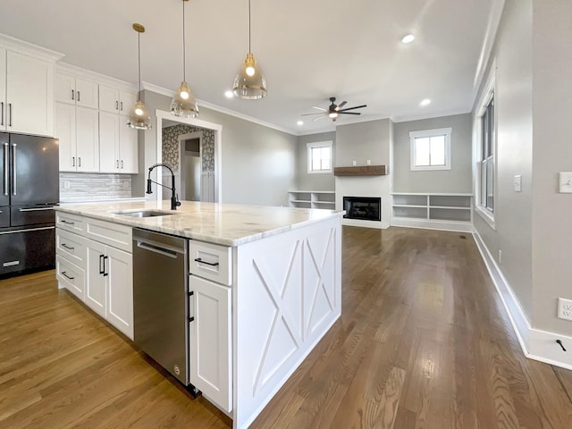 kitchen featuring white cabinetry, sink, high end refrigerator, stainless steel dishwasher, and a center island with sink