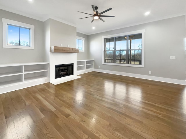 unfurnished living room featuring ornamental molding, hardwood / wood-style floors, ceiling fan, and built in shelves