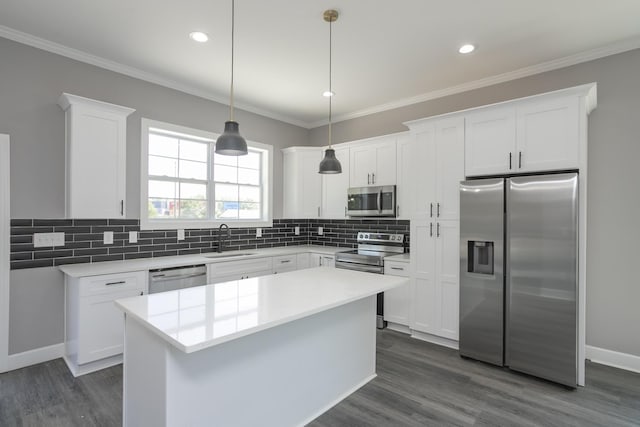 kitchen with sink, white cabinetry, decorative light fixtures, appliances with stainless steel finishes, and a kitchen island