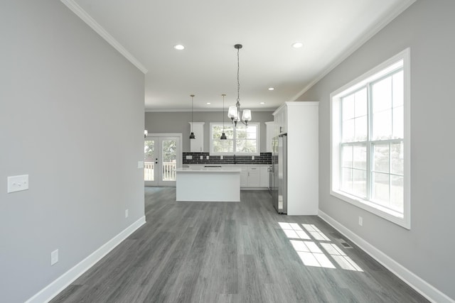 unfurnished living room featuring french doors, dark wood-type flooring, sink, a chandelier, and ornamental molding