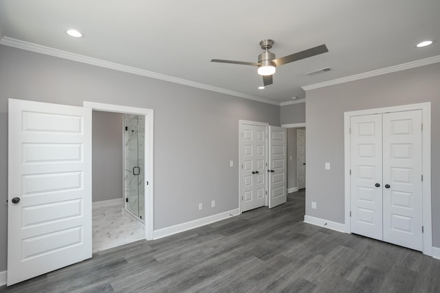 unfurnished bedroom featuring ceiling fan, dark hardwood / wood-style floors, connected bathroom, ornamental molding, and multiple closets