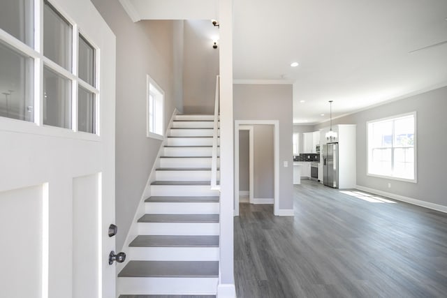 stairway with ornamental molding and wood-type flooring