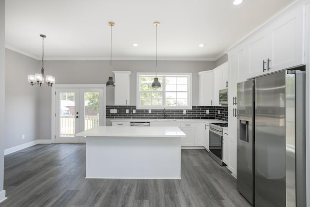 kitchen with white cabinetry, appliances with stainless steel finishes, decorative light fixtures, and a kitchen island