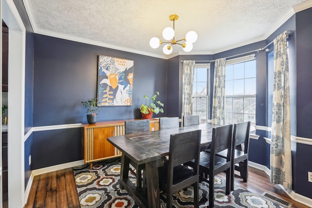 dining room with an inviting chandelier, wood-type flooring, crown molding, and a textured ceiling