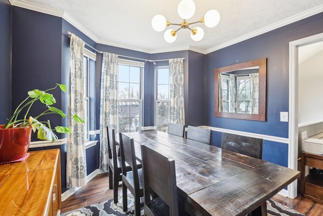 dining area featuring dark wood-type flooring, ornamental molding, a chandelier, and a textured ceiling